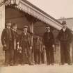 View of six men, some in railway uniform, on station platform, possibly in Stanley.