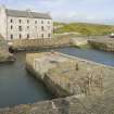 Elevated view looking across Keiss inner harbour and centre pier to the warehouse, taken from S