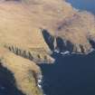 General oblique aerial view of  the remains of Dun Mingulay and the remains of the head dyke, field system, lazy beds, pens and enclosures around Skipisdale, south Mingulay, taken from the W.