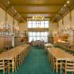 Interior. View looking along the length of the dining hall to the reception desk and servery.