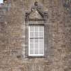 Detail of window with carved stone pediment on north gable of west facade