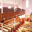 General view from rear gallery, looking along side gallery and down onto pews and central pulpit.
