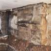 Interior. View of blocked fireplace at ground floor, with (possibly re-used) large lintel stone and re-used stone capital within quoins.