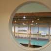 Interior. Detail of porthole within central corridor wall, looking into carpet bowls hall.