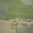 Oblique aerial view of Athelstaneford village with the cropmarks of possible buildings and road adjacent, looking N.