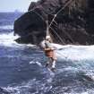 Martin Roberts in the cable suspended breeches buoy to Dun, St Kilda, 1974.