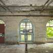 Interior. 1911 extension/rebuild west external wall of former one storey west range. View of arched doorway and windows. Concrete floor and drain visible.