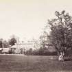 View of back of St Germains House and glass house with lady on lawn.