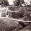 View of stream with footbridge and greenhouse in walled garden, St Germains House.