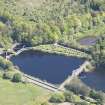 Oblique aerial view of Mugdock Resevoir measuring pond, footbridge and sluice , looking NNE.