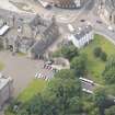 Oblique aerial view of Thomson's Court, Holyrood Palace Gatehouse, James IV's Tower Abbey Sanctuary, Holyrood Palace Yard Fountain and Holyrood Free Church and School, looking SSW.