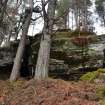 A rock shelter built into a rock outcrop with south east facing aspect; a plaster angel figure sits on a ledge above it, Inchnacardoch Forest Block, South Loch Ness