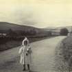 View of young girl standing on road, possibly near Neidpath Castle