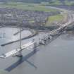 Oblique aerial view of the construction of the Queensferry Crosssing at the south bank of the River Forth, looking SE.