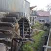 Waterwheel and lade, view from south west and the red monopitch roof of the electricity generating house and the turning mill beyond