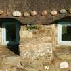 Detail of thatching above window showing stone weights; restored19th century thatched cottage, Tiree, Kilmoluaig.