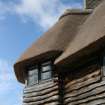 Detail of roof and chimney corner showing wooden boarding below thatch; Bolton Muir.