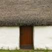 View of side wall and door showing thatched roof above; Tullochard, Plockton.