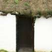 Detail of thatched roof above door, showing stone weights and vegetation growth; Giant McAskill Museum, Dunvegan.