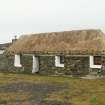 Front view of probable 19th century marram thatched cottage with stone weights; Laimrig Ruadh, Berneray.