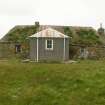 View of 19th century thatched cottage in poor condition, with modern porch extension; 99 Carnan South Uist.