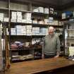 Portrait of Mr Alexander Hunter at his shop counter.