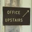 South range, south (customer) entrance. Detail of sign with arrow pointing to upstairs office