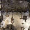 View of selection of tools hanging on wall above powered hammer. This includes 'scrap' iron objects.
