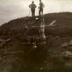 Photograph of two men standing on top of the entrance to Hillhead Broch. 