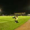 General view of football pitch to north and west terracing taken from the east. Under floodlights.