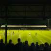 General view of the west covered terracing with the 'away' fans with views to the football pitch and east terracing taken from the west. Under floodlights.