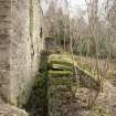 View from north west of water wheel pit. Lade supports in background, tailrace in foreground.