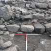 Outermost wall in foreground, with outer outer wall behind, notably large boulder on left, and broch outer wall at back