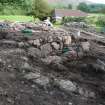 In foreground, compacted rubble and earth of possible later ramp corresponding to linear bank exposed in 2008, in background, outer wall and outer outer