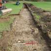 Evaluation photograph, SW end of trench 1 showing shallow topsoil and deep modern plough marks and trench 2 started, Land to SW of Birse Church, Birse, Aboyne