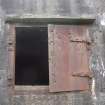 A sheet metal window shutter on the ENE wall of the Post War command shelter peppered by shot