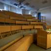 Main block. Ground floor. Lecture theatre. View of bench seating with canted bay to rear and upper entrance from main staircase quarter landing. 