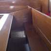Detail gallery front pew with doorway closed and hinged pew seat down.