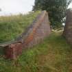 Explosives Magazine R49: the W entrance for the narrow gauge railway through the blast wall showing the restored brickwork around the crest of the S revetment and the concrete revetment opposite