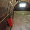 Interior, W3: view along the ESE wall to the SSE gable-end of the building showing the plywood panelling between the iron ribs, the gutter at the edge of the cement floor and the rectangles marking the latter’s repurposing for the WW2 ammunition magazine