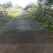 View S over a modern cattle grid (NY 26741 65039) on road north of Nitroglycerine Hill 3 and showing the dense deciduous covered landscape