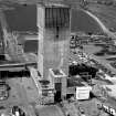 View from S showing top of No. 1 winding tower of No. 2 winding tower, built of re-inforced concrete, and used to wind men and materials using a tower-mounted, geared, A.C. multi-rope friction winder with cage and counterweight, manually controlled, with dynamic braking.  Part of the fanhouse is visible behind the tower.