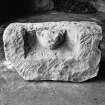 View of dressed sandstone block with coped sides and bearing a cat like head in high relief, held in the garage behind the manse.