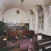 Interior-view from West of chapel showing wooden panelling and stained glass panels in windows.