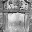 View of gravestone 'Marion McKenzie d.1767' (Ross) showing carved tools and two figures, possibly surveying. 
