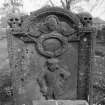 Reverse face, gravestone of George Mortoun, d.1728. Skulls on shoulders, winged cherub within pediment, portrait in relief.