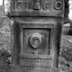 Front face, gravestone bearing intitials I H and A G, d.1710. Hourglass between initials and date. Weaver's loom bearing MEMENTO MORI inscription, death mask or portrait carved in relief.