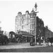 Morningside Road Station.
View from South East.
Titled: 'Morningside Road Railway Station in 1900.'
Caption (beneath): 'Note the horse-drawn Tram-car to left; the trace horses and boys used in helping the car to the top of the slope to Church-hill, and the type of arc lamp used for street illumination then.'