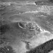 Snaip Hill, oblique aerial view, taken from the W, centred on the remains of fort, enclosure and possible hut circle.