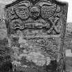 Gravestone dated 1760. Winged cherub; skull in profile, coffin, winged hourglass, crossbones; set-square and compasses.